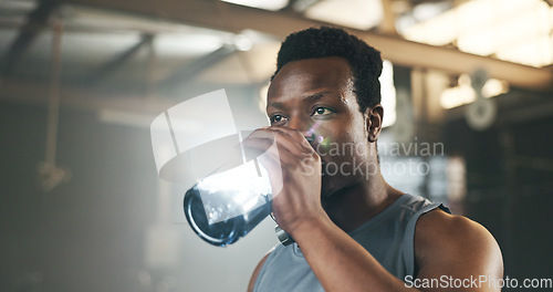 Image of Black man at gym, water bottle and relax to hydrate in muscle development, strong body and fitness. Commitment, motivation and bodybuilder with drink in workout challenge for health and wellness.