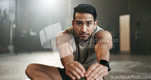 Image of Man stretching on floor of gym for strong body, muscle development or balance in power fitness. Commitment, motivation and focus on ground, bodybuilder in energy training workout and exercise mindset