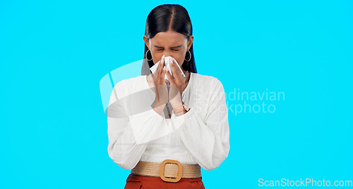 Image of Woman, blowing nose and sick with tissue in studio for allergies, dust or pollen by blue background. Girl, sneeze and toilet paper with pain, virus and cold for healthcare, wellness and flu symptoms