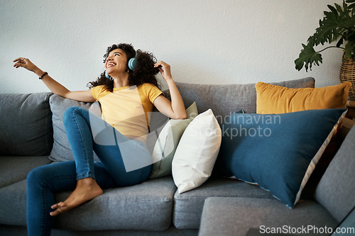 Image of Happy, freedom and woman on a sofa with music, headphones or subscription at home. Podcast, earphones and female person having fun with radio, streaming or online audio, track or album in living room