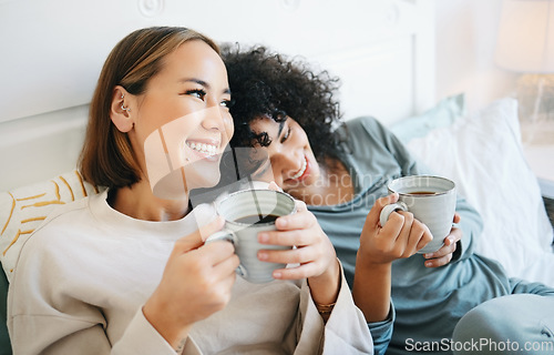 Image of Coffee, communication and happy lesbian couple on bed bonding and relaxing together. Happy, rest and young interracial lgbtq women laughing, talking and drinking latte in bedroom of modern apartment