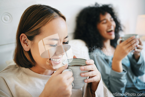 Image of Coffee, smile and lesbian couple on bed in conversation for bonding and relaxing together. Happy, rest and interracial lgbtq women laughing, talking and drinking latte in bedroom of modern apartment.