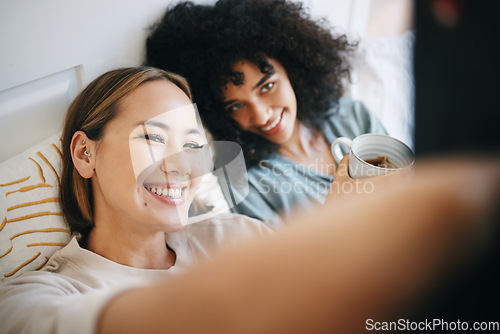 Image of Love, selfie and lesbian couple relaxing on bed for bonding together in the morning on weekend. Smile, happy and young interracial lgbtq women taking a picture in bedroom of modern apartment or home.