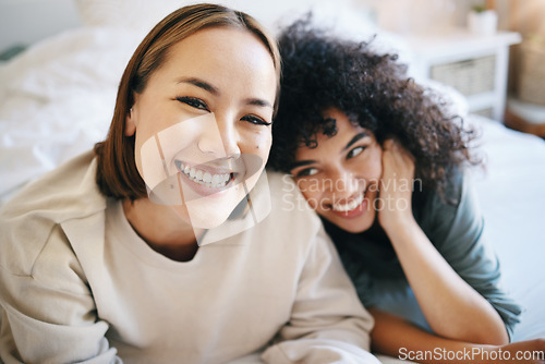 Image of Love, happy and portrait of lesbian couple relaxing on bed for bonding together on a weekend. Smile, romance and young interracial lgbtq women resting in the bedroom of modern apartment or home.