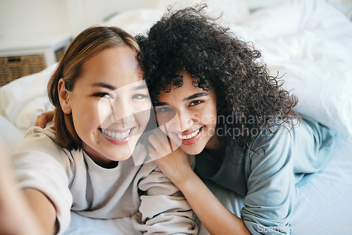 Image of Smile, selfie and portrait of lesbian couple on bed for bonding, resting or relaxing together. Happy, love and young interracial lgbtq women taking picture in the bedroom of modern apartment or home.