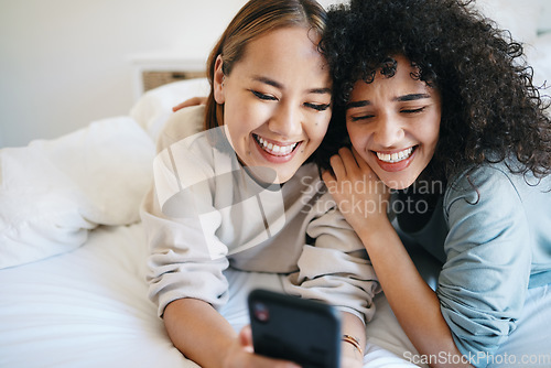 Image of Cellphone, relax and young lesbian couple in bed networking on social media, mobile app or the internet. Happy, technology and interracial lgbtq women scroll on a phone in bedroom at modern apartment