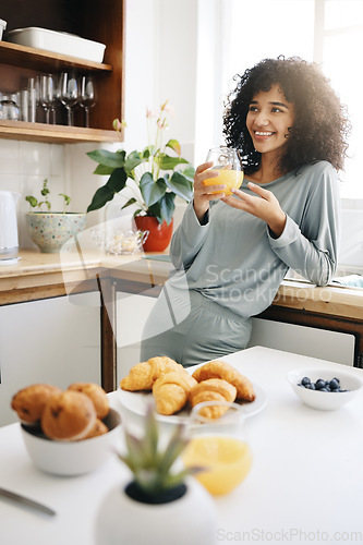 Image of Woman, smile and thinking with orange juice in kitchen for breakfast, nutrition and vitamin c in the morning. Food, person and happiness with idea and drink with pajamas or natural face for wellness