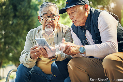 Image of Senior men, friends and phone in park, reading and talk with memory, thinking and relax in sunshine. Elderly people, smartphone and talking on bench, nostalgia and check social media notification