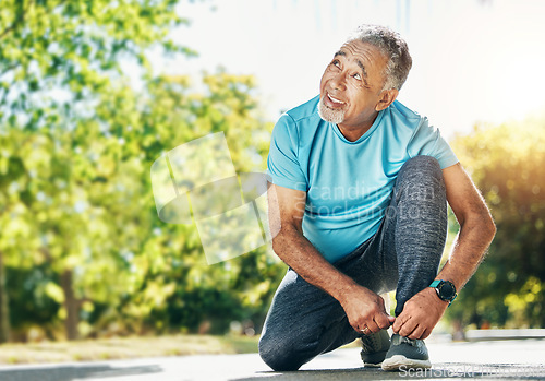 Image of Tying laces, man and in a park for running, exercise and getting ready for outdoor cardio. Smile, idea and a mature or senior male athlete with shoes in the street for a workout, exercise or training