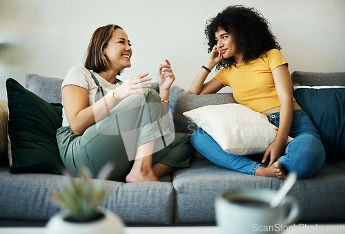 Image of Women, friends relax and conversation in a home with gossip, discussion and happy in a living room. Couch, smile and female person on sofa with communication together in a house lounge with speaking