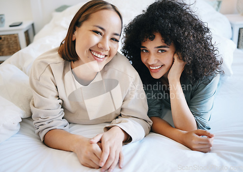 Image of Love, smile and portrait of lesbian couple on bed for bonding, resting and relaxing together. Happy, romance and young interracial lgbtq women laying in the bedroom of modern apartment or home.