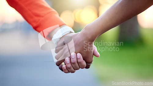 Image of Interracial couple, holding hands and love in nature for support, trust or unity together. Closeup of people touching in romance, care or friendship walk in an outdoor park for partnership or duo