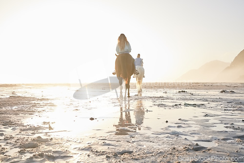 Image of Woman, horse riding and friends on beach with sand for travel, vacation or holiday trip outdoor in nature. Back, people and animal in summer with lens flare by ocean or sea for sunset and travelling