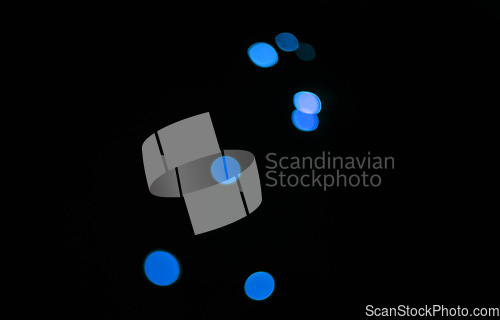 Image of Bokeh, blue dots and black background with glow or sparkle, mockup space with light, texture and flare from festival. Glitter, art and texture with graphic design, special effects on dark backdrop