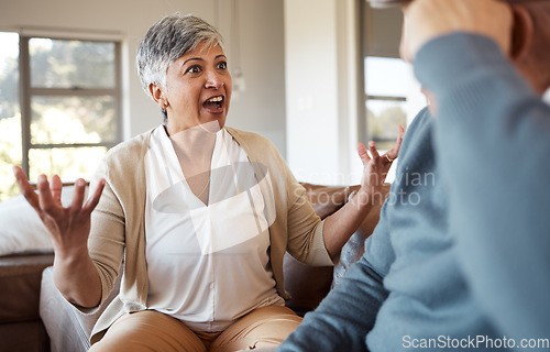 Image of Divorce, fight and senior couple on a sofa angry, shouting and frustrated in their home together. Marriage, crisis and elderly people in a living room argue, stress and anxiety for debt, risk or liar