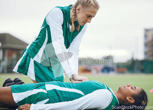 Image of First aid, cpr and accident with a hockey player on a field to save a player on her team during an emergency. Fitness, sports and heart attack with a woman helping her friend on a field of grass