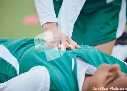 Image of Hands, first aid and cpr with a hockey player on a field to save a player on her team after an accident. Fitness, heart and emergency attack with a woman helping her friend on a field of grass