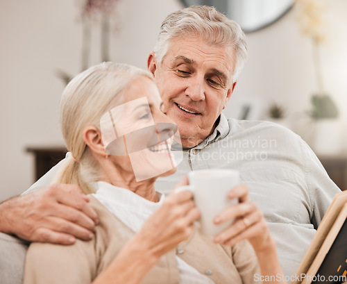 Image of Senior couple, coffee and reading book on a sofa with love, smile and retirement in a home. Elderly people, communication and lounge on a couch with study for knowledge in a house happy and relax