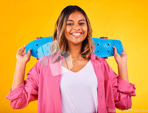 Image of Woman, portrait and smiling with skateboard on yellow studio background, skater and excited. Cool, gen z face and happiness to skate, play and enjoy free time, in fashion clothes, outfit and stylish