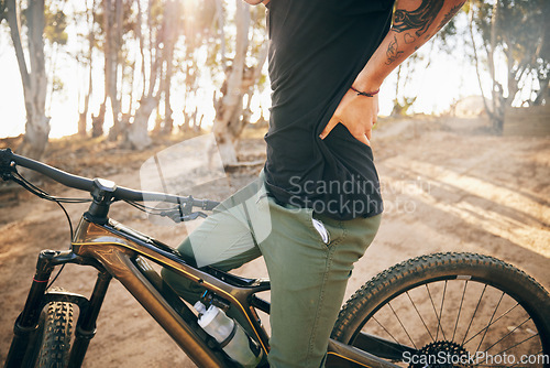 Image of Cycling, man and bike with back pain in nature of training, exercise and workout outdoor in forest. Bicycle, person and fitness with injury from adventure, travel and strain in summer or woods