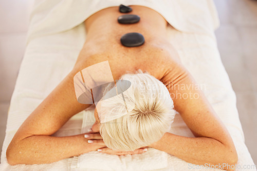 Image of Senior woman, spa and wellness with stone, massage and relax with health, stress relief and luxury. Salon treatment, elderly person and pensioner with care, resting and spine with beauty and rock