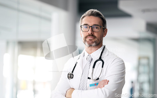 Image of Serious doctor, portrait and man with arms crossed in hospital for healthcare, wellness or career. Face, medical professional and confident surgeon, expert and mature employee in glasses in Canada