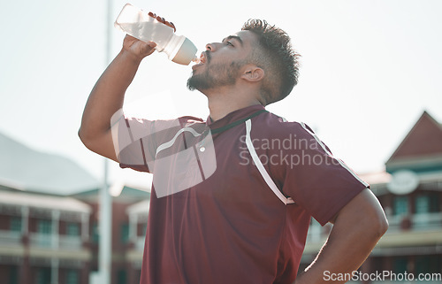 Image of Football player, drink water and rest on sports field for training completion, workout and exercise outdoors. Fitness, workout and male athlete with liquid bottle for wellness, hydration or practice