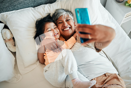 Image of Selfie, smile and grandmother with child on bed bonding, relax and love for happy family with care. Photography, technology and senior woman with little girl in bedroom on video call together in home