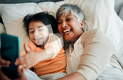 Image of Selfie, smile and old woman with child on bed bonding, relax and love for happy family with care. Photography, technology and grandmother with little girl in bedroom on video call together in home