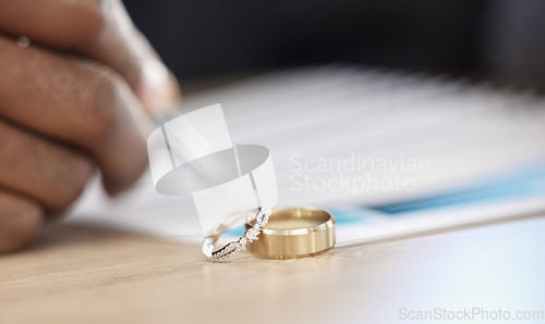 Image of Divorce, rings and signature on paperwork for a lawyer, register wedding or writing on a contract. Table, closeup and a certificate, planning or legal documrnts for a commitment or engagement