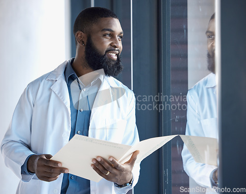 Image of Doctor, black man and thinking of healthcare information, paperwork or documents by window in building with smile. Person, professional or person thoughtful of notes or charts on paper with ideas