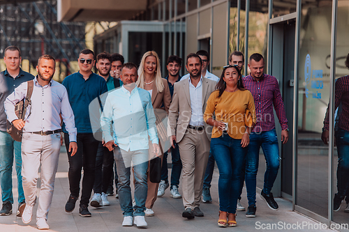 Image of A diverse group of businessmen and colleagues walking together by their workplace, showcasing collaboration and teamwork in the company.