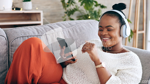 Image of Black woman on couch, headphones for music and smartphone, relax at home and audio streaming with smile. Happiness, mobile app and using phone for radio or podcast, scroll with technology in lounge