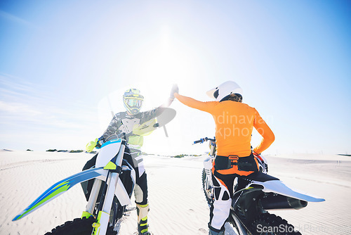 Image of Extreme sport, motorcycle and desert with high five for achievement, skill and teamwork with success. Biker, sunshine and sand with adrenaline, fitness and congratulations for speed with training