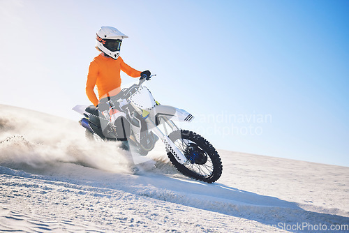 Image of Sport, motorbike and athlete with desert with sand on wheels, pride and skill for adrenaline. Biker, sunshine and dust with blue sky in fun, fitness and achievement in speed, race or dubai vacation