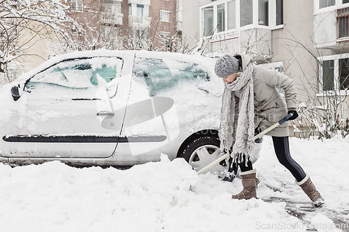 Image of Independent woman shoveling snow in winter.