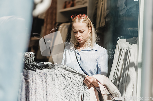 Image of Beautiful woman shopping fashionable clothes in clothing store.