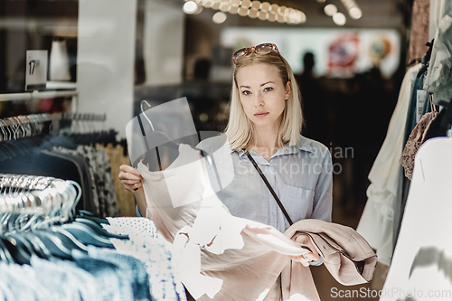 Image of Beautiful woman shopping fashionable clothes in clothing store.