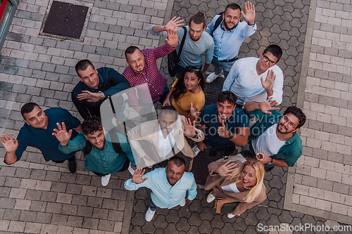 Image of A top view photo of group of businessmen and colleagues standing together, looking towards the camera, symbolizing unity and teamwork.