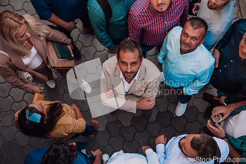 Image of A top view photo of group of businessmen and colleagues standing together, looking towards the camera, symbolizing unity and teamwork.