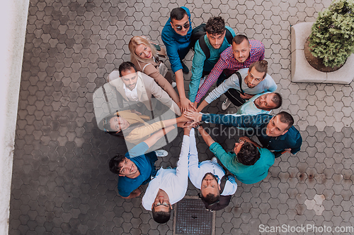 Image of Top view photo of a group of business people and colleagues standing together holding hands, looking towards the camera, symbolizing unity and teamwork.