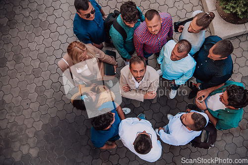 Image of A top view photo of group of businessmen and colleagues standing together, looking towards the camera, symbolizing unity and teamwork.