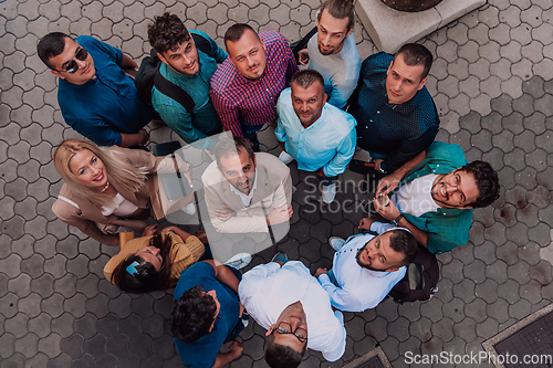 Image of A top view photo of group of businessmen and colleagues standing together, looking towards the camera, symbolizing unity and teamwork.