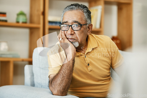 Image of Face, mental health and thinking with a sad old man on a sofa in the living room of his retirement home. Depression, alzheimer or dementia and a senior person looking lonely with memory nostalgia