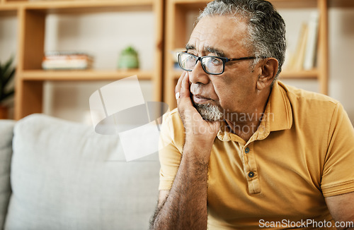 Image of Face, depression and thinking with a sad old man on a sofa in the living room of his retirement home. Mental health, alzheimer or dementia and a senior person looking lonely with memory nostalgia