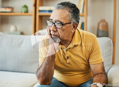 Image of Face, depression and alzheimer with a sad old man on a sofa in the living room of his retirement home. Mental health, thinking or dementia and a senior person looking lonely with memory nostalgia