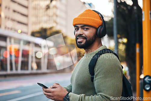 Image of Phone, headphones and portrait of man in city outdoor, listen to audio or radio sound on internet to travel. Face, streaming music and happy student typing in street on social media in South Africa