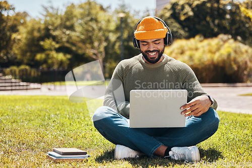 Image of Student, laptop and headphones in university park, college or school for research, studying and e learning on grass. African man on computer, listening to music or campus podcast for online education