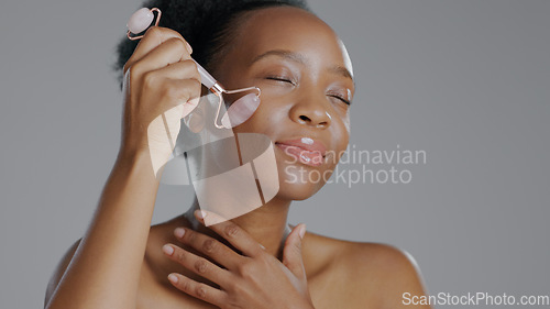 Image of Black woman, face with roller and massage for beauty and skincare, natural cosmetics and treatment on white background. Wellness, dermatology and skin glow, rose quartz crystal and tools in studio