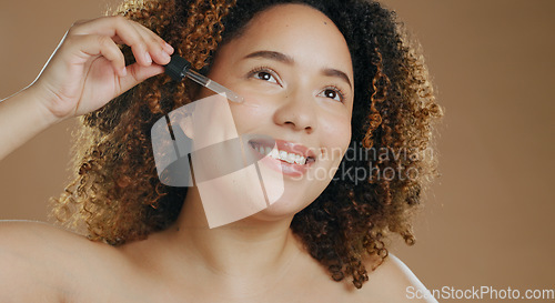 Image of Happy woman, pipette and face serum for skincare, cosmetics or glow against a studio background. Female person smile applying facial oil in dermatology, beauty or skin treatment in health or wellness